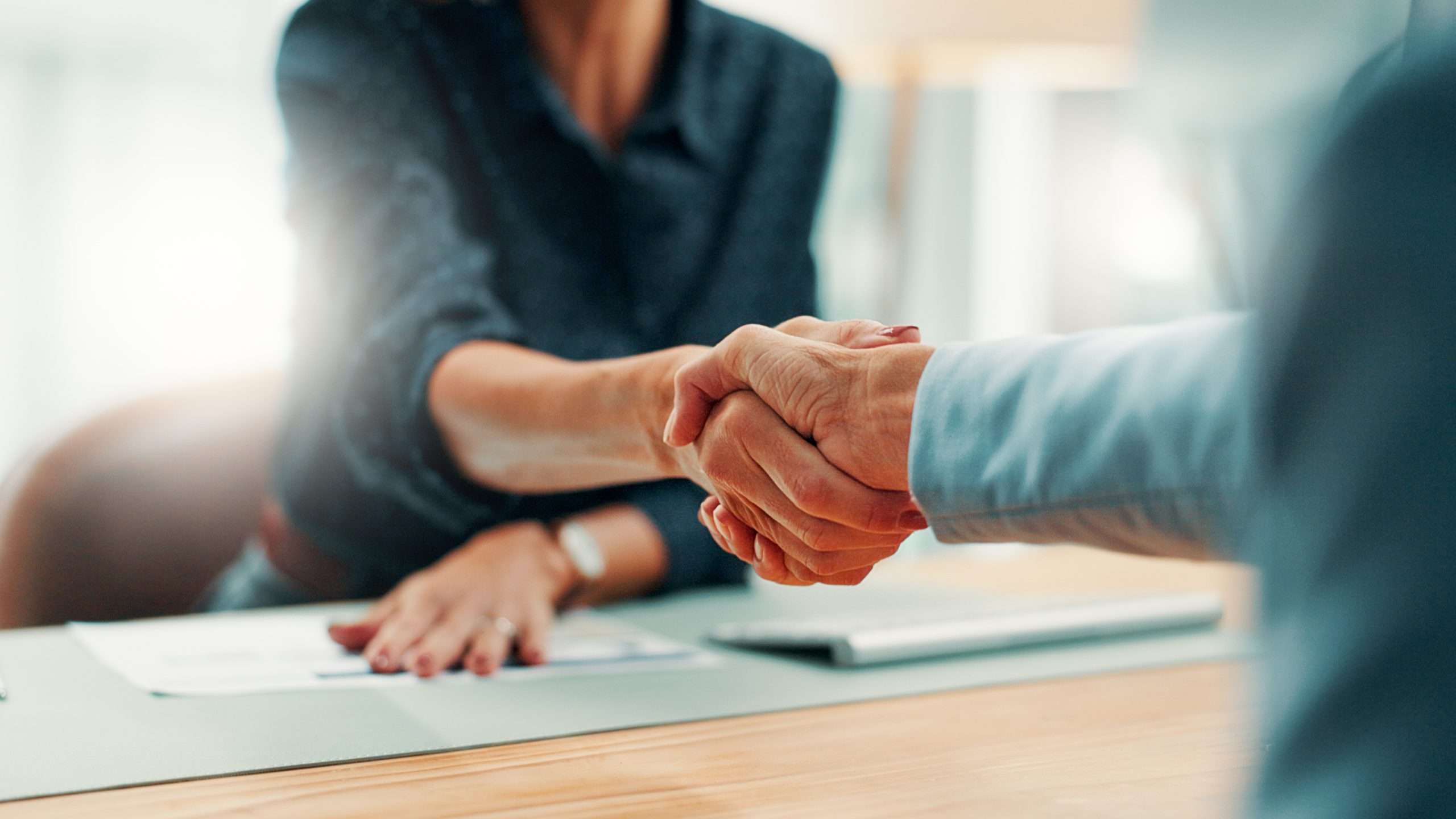 Handshake, deal and business people in office with agreement, contract or finance partnership. Meeting, welcome and financial advisor shaking hands with investor for investment negotiation at agency