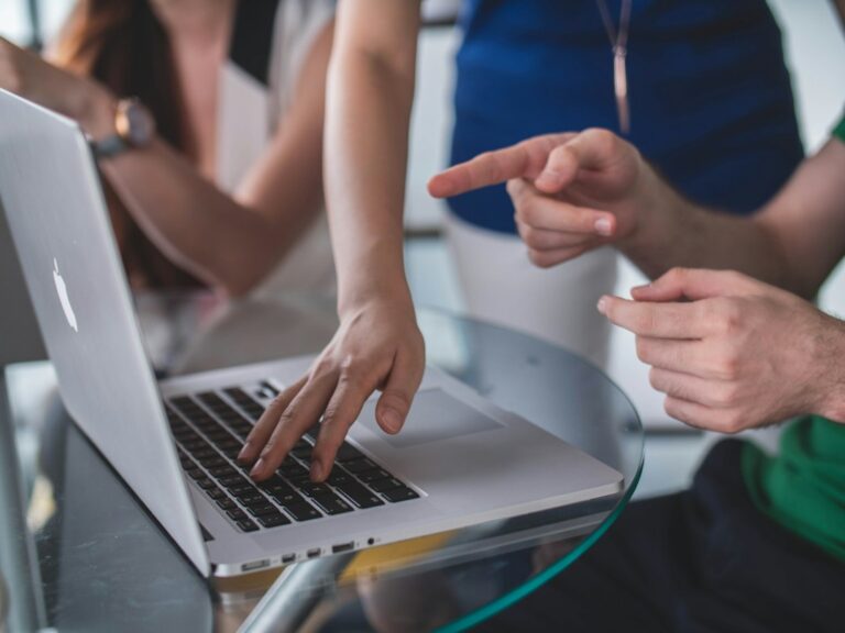 Hands collaborating over an open laptop
