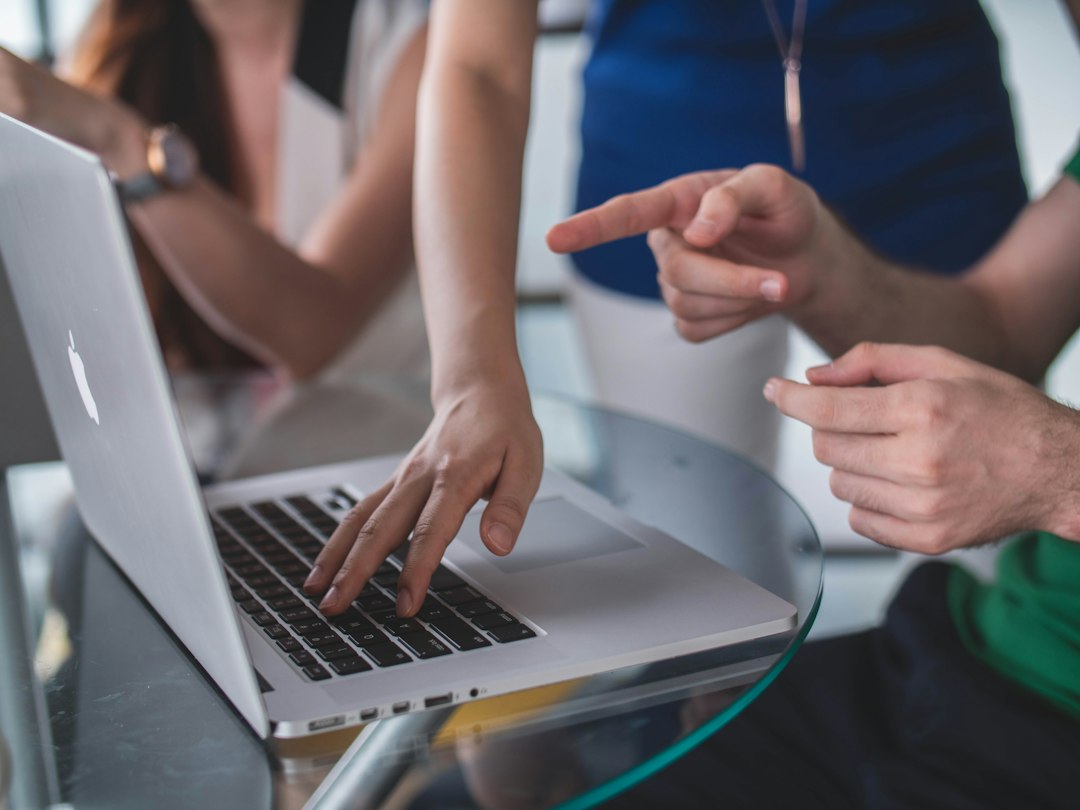 Hands collaborating over an open laptop